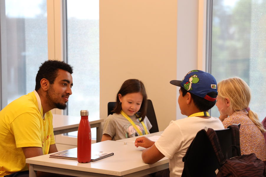 en person og et par barn som sitter ved et bord